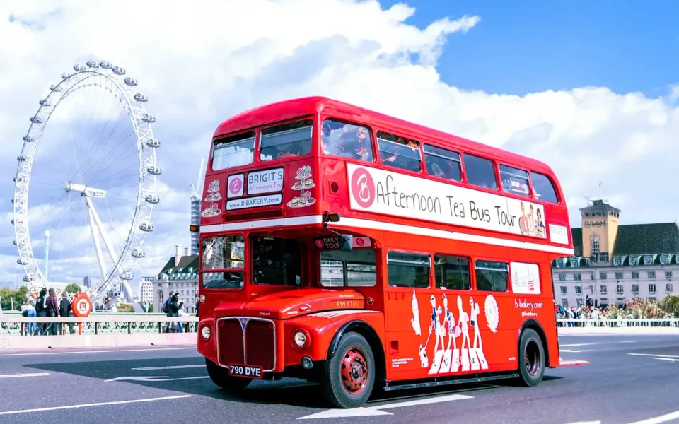 Ein roter Afternoon-Tea-Bus neben dem London Eye