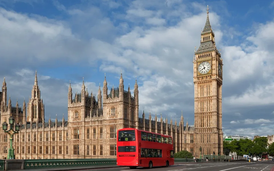 Ein Doppeldeckerbus neben dem Palace of Westminster